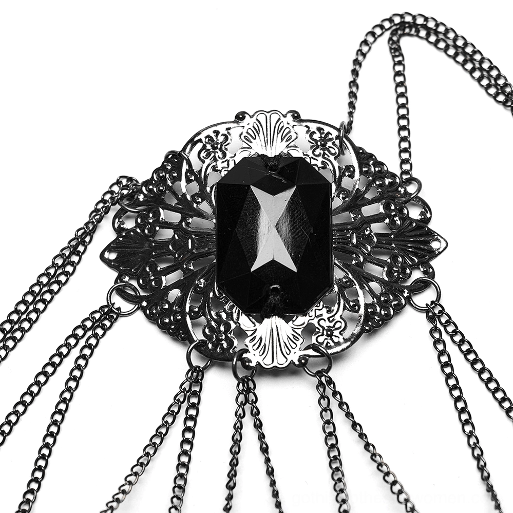 Macro close-up detail of gothic jewelry centerpiece featuring large faceted black gemstone in ornate metal frame with multiple attached chain tassels