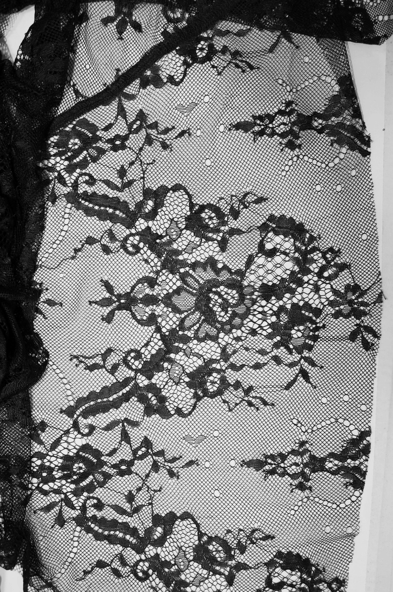 Close-up detail of floral damask lace pattern and sheer mesh fabric with pearl beading accents on gothic dress