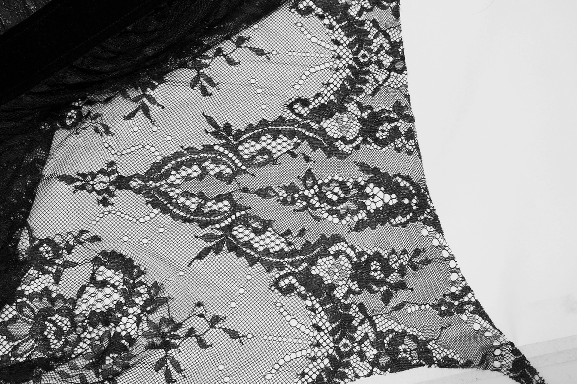Close-up of damask floral lace fabric pattern on sheer mesh base of gothic dress showing intricate construction