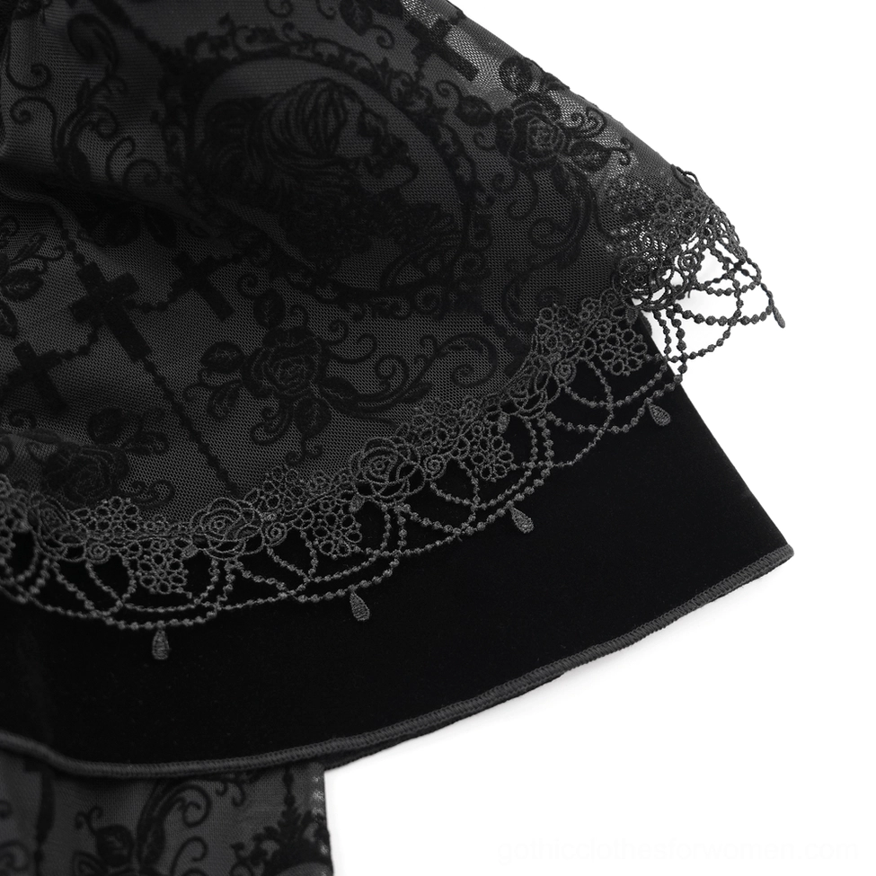 Intricate close-up of cross and rose-patterned lace fabric with scalloped trim detail on black gothic dress