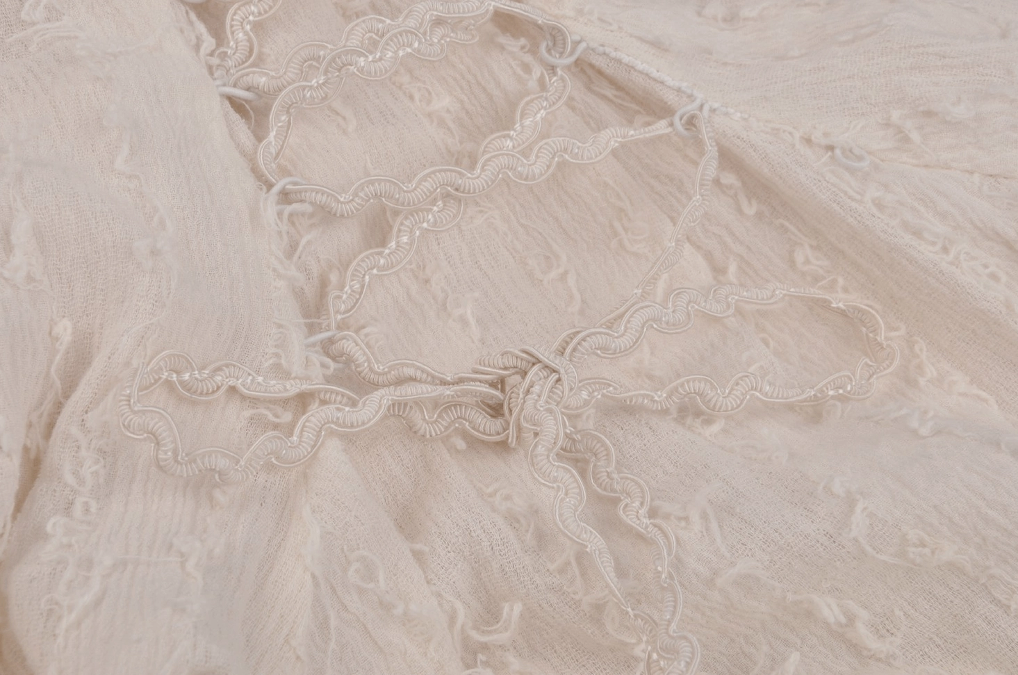 Macro photograph of cream woven lace with rickrack embroidery trim detailing gothic dress fabric