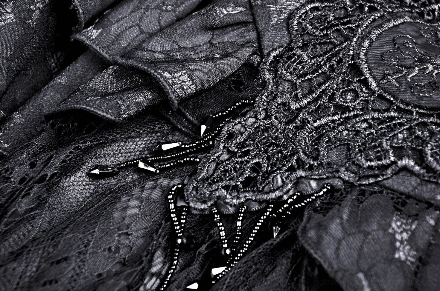 Close-up macro shot of intricate black floral lace texture with beaded accents on satin ruffles