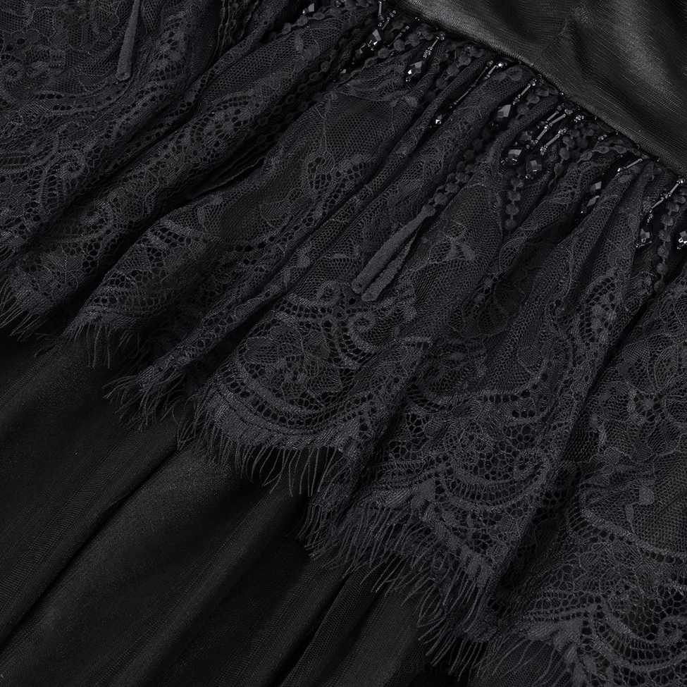 Close-up detail of intricate black lace fabric with floral pattern and frayed fringed edge on satin base