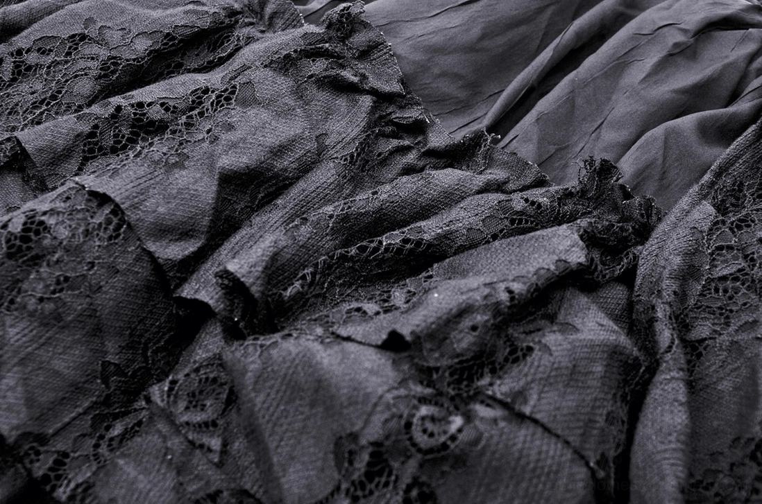 Black gothic skirt fabric close-up showing woven textile blend with lace overlay pattern
