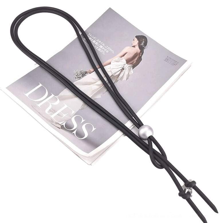 Long gothic lariat necklace with black rubber cord and silver bead placed on fashion magazine styling