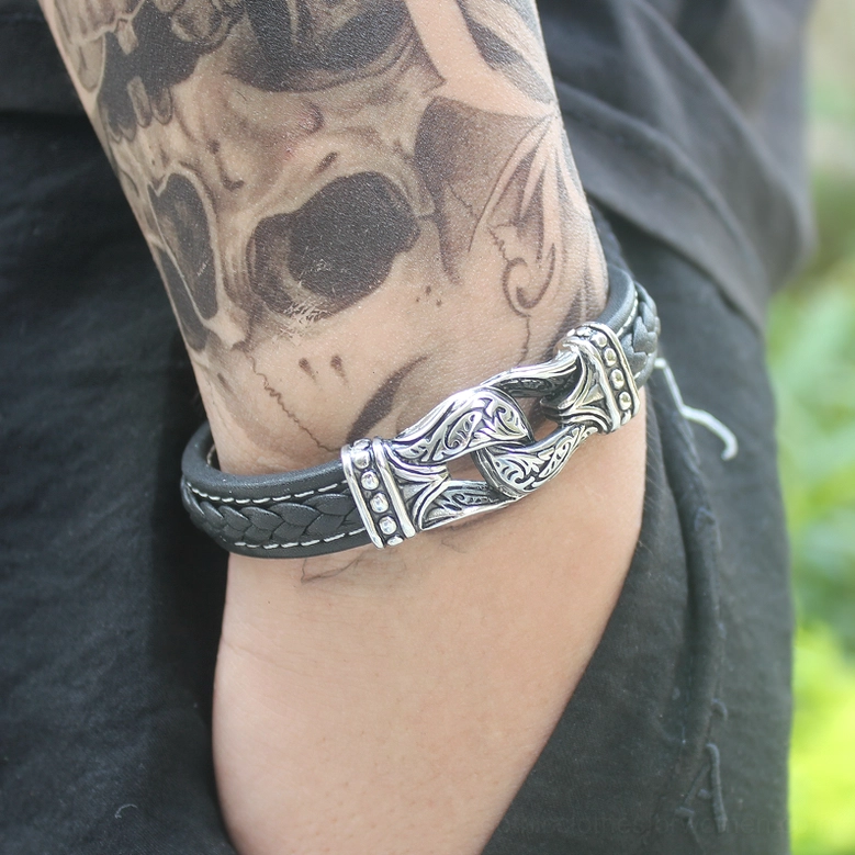 Close-up of gothic leather bracelet on tattooed male forearm, showing leather texture and stainless steel clasp