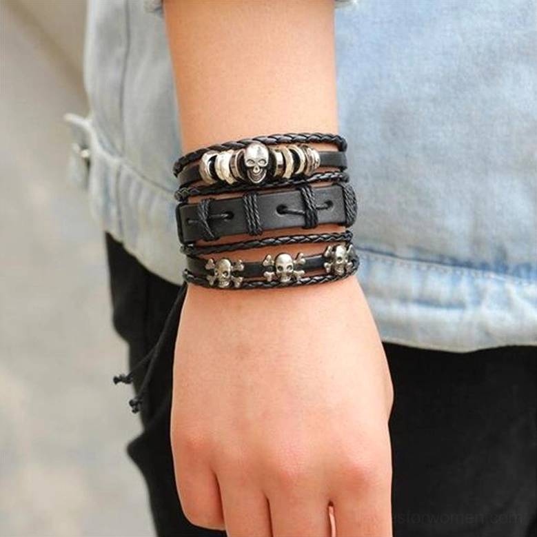 Woman wearing layered black gothic leather bracelets on wrist in casual daily wear setting, showing skull and star designs on human model
