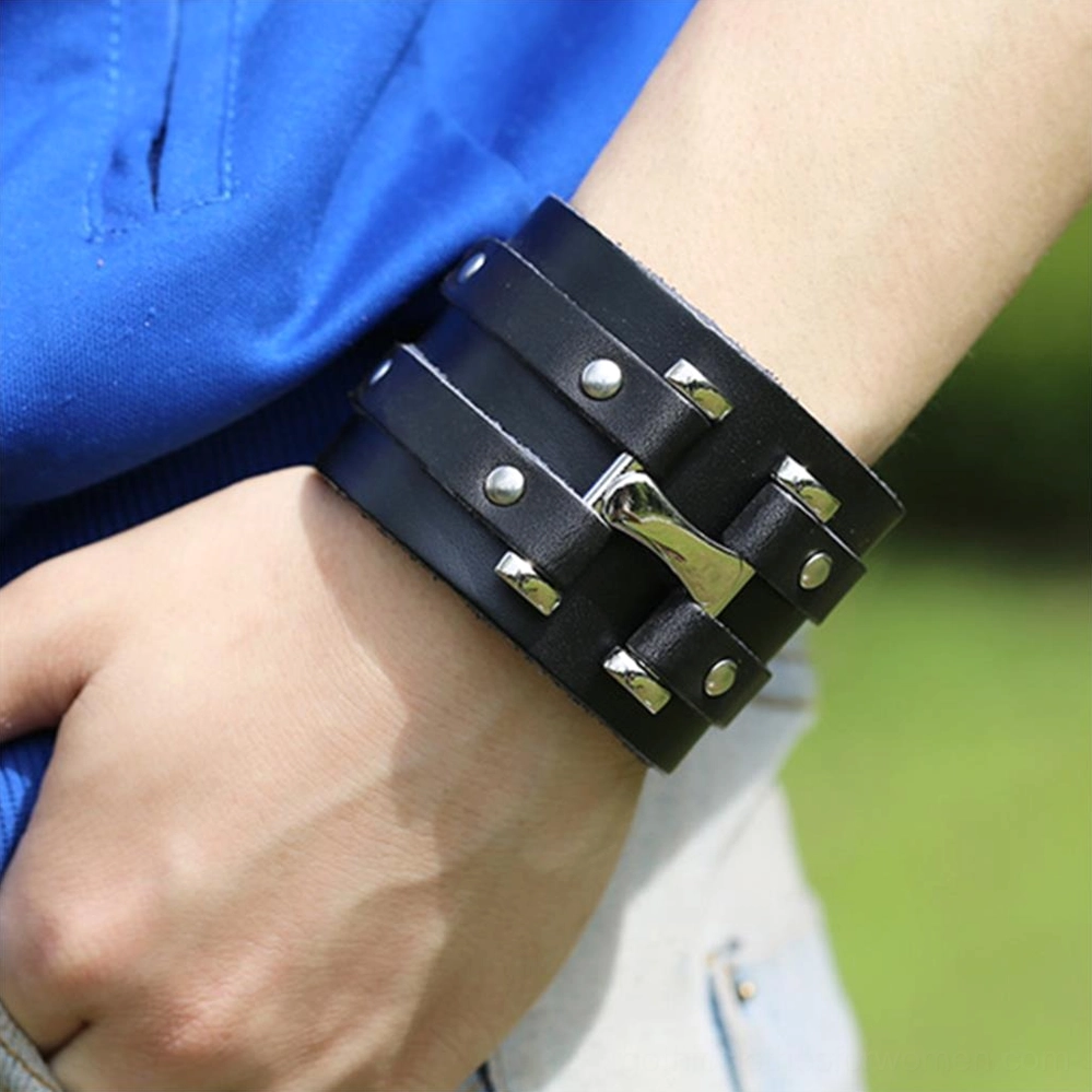 Black leather punk rock bracelet worn on male wrist, outdoor casual setting, demonstrating fit and real-world styling with silver hardware visible