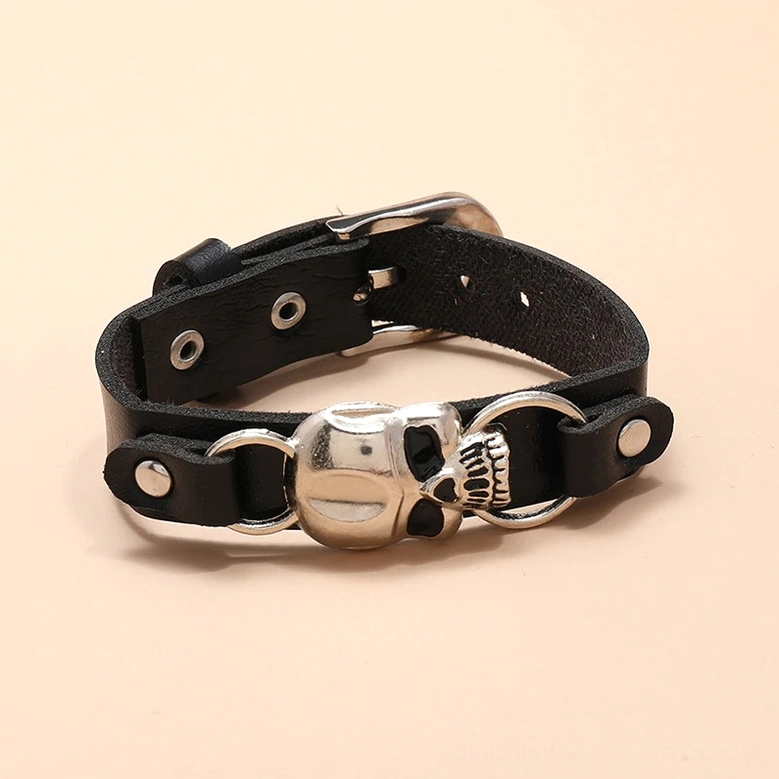 Flat lay overhead view of gothic skull leather bracelet with brass-toned skull and dual ring hardware
