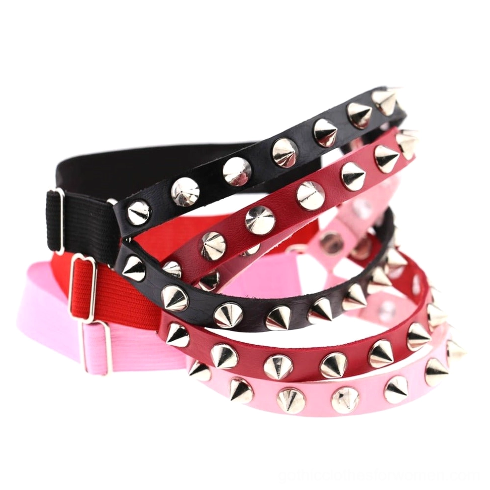Multi-color spiked leg garters display featuring black, red, pink, and blue leather options with silver cone and round rivets in overhead flat lay