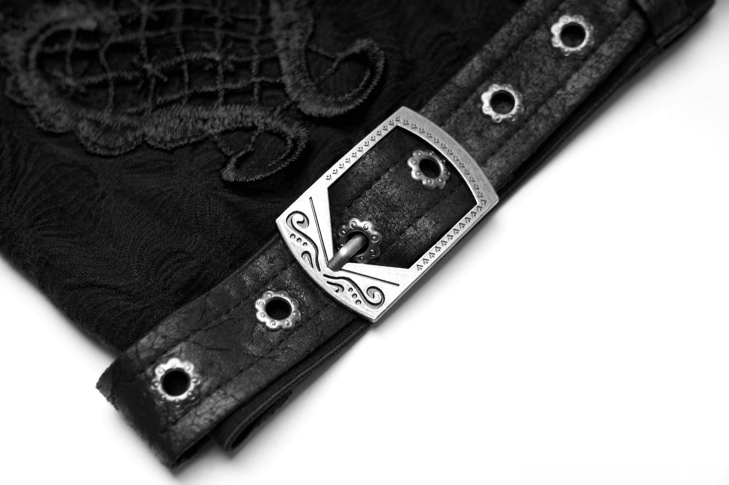 Close-up macro shot of metal buckle hardware with vintage engraved detailing and faux leather strap on leg warmer