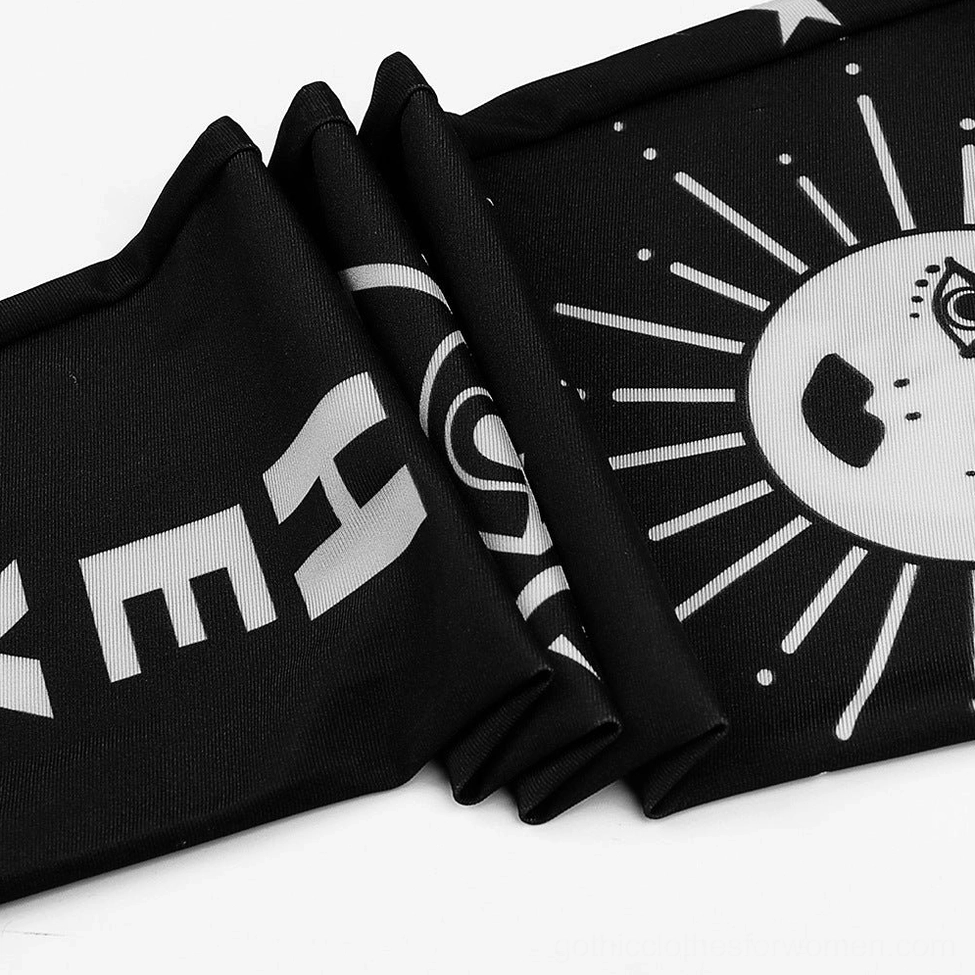 Flat lay detail of black gothic leggings showing stretchy fabric and white occult symbols, crosses and celestial patterns