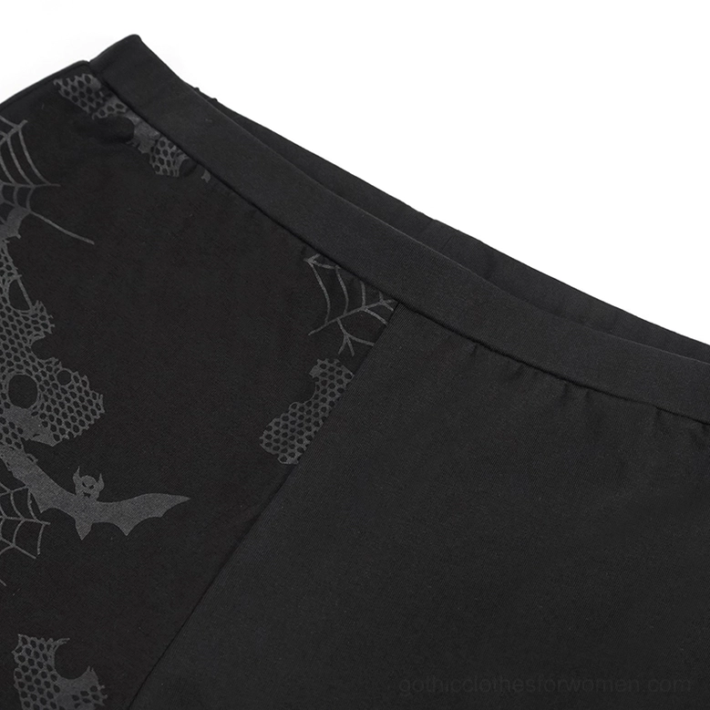 Close-up detail of black gothic leggings fabric showing spooky horror-inspired print design and neat seam stitching quality