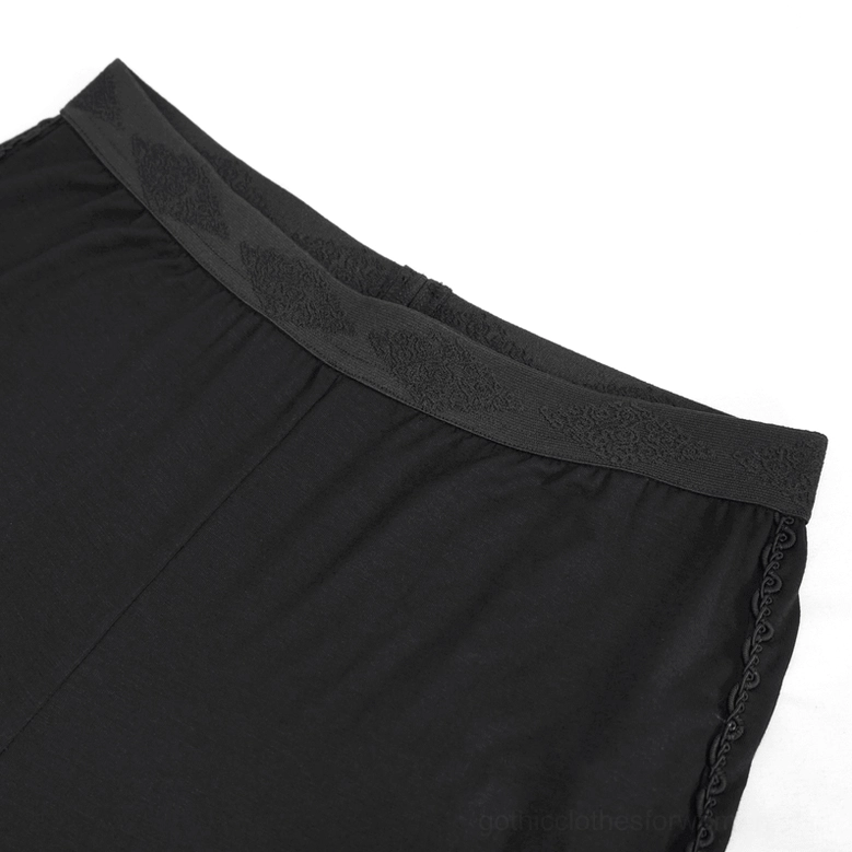 Close-up of embroidered patterned waistband and black braided decorative trim on gothic leggings