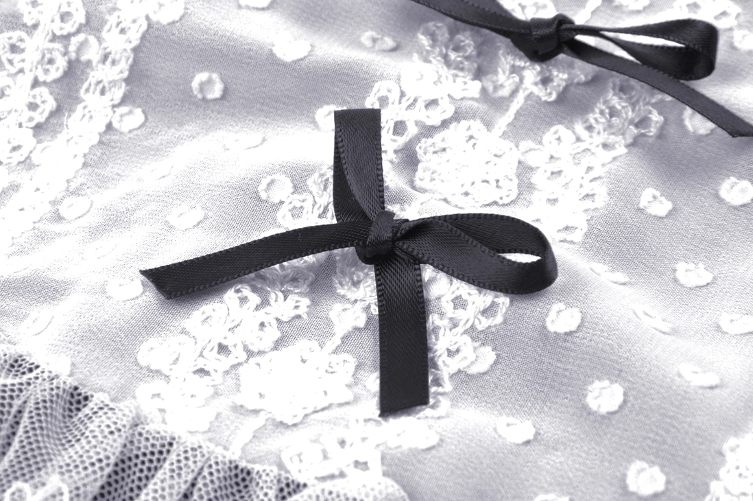 Detailed view of dress fabric showing dot embroidered mesh and tiny satin bow accent