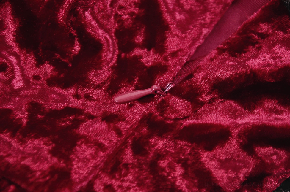Detailed close-up of dress hem showing asymmetrical cut, black lace trim, and ruffled velvet edge finishing
