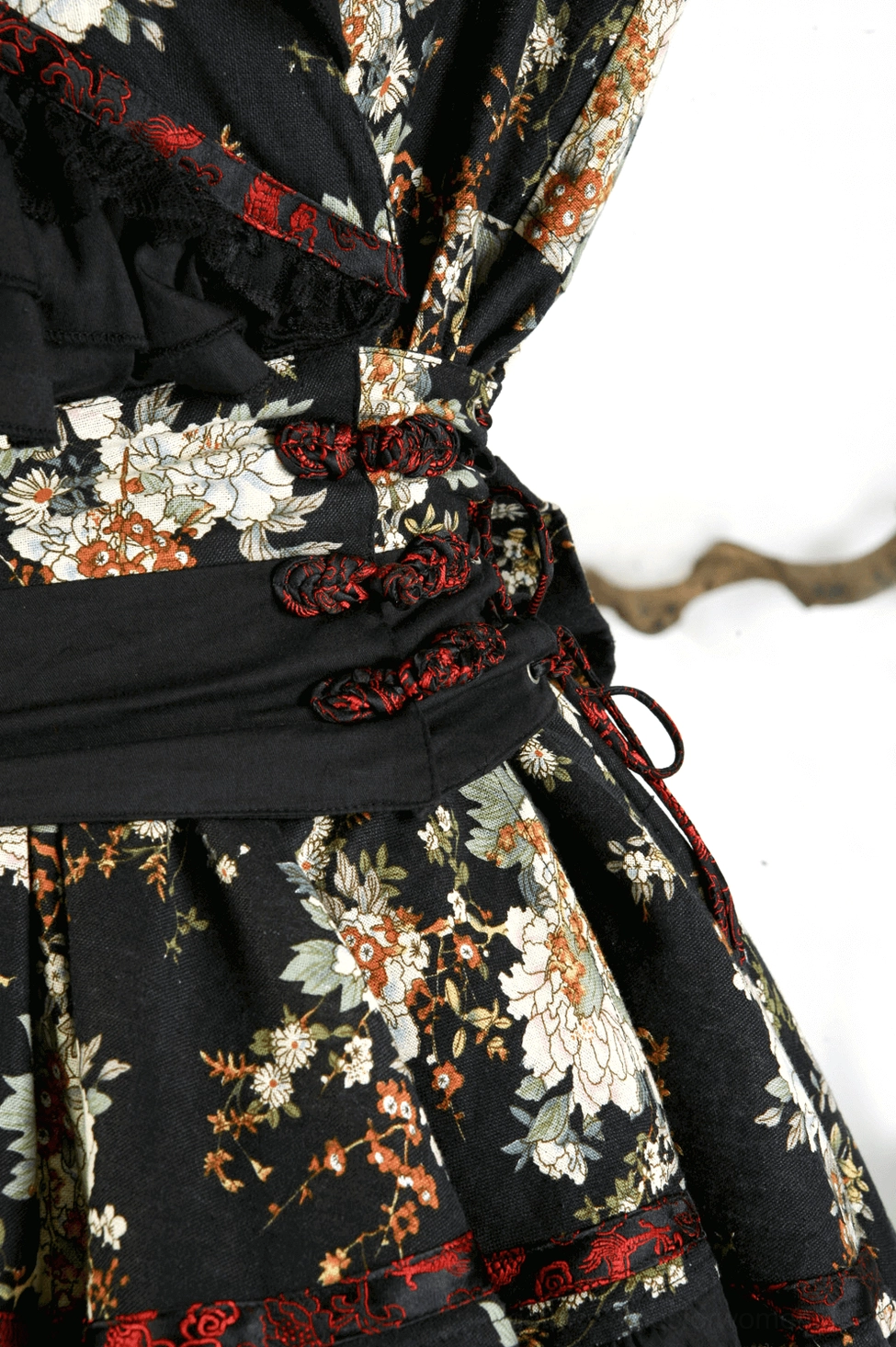 Black floral gothic lolita dress detail shot highlighting ruffled trim and fabric texture