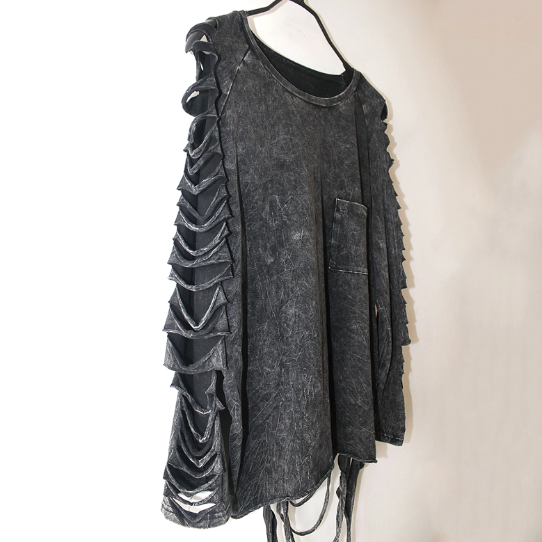 Hanging side view of black gothic t-shirt with distressed cutout sleeves and tassel hem detail against studio background