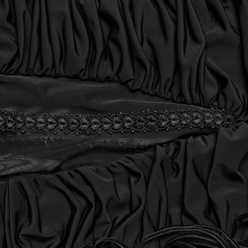 Detailed close-up of embroidered lace strip on ruched black fabric of gothic maxi skirt
