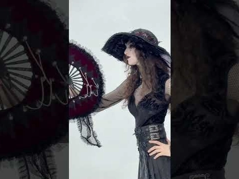 Female model wearing black gothic maxi skirt styled with wide brim hat in vintage studio setting demonstrating complete gothic aesthetic look