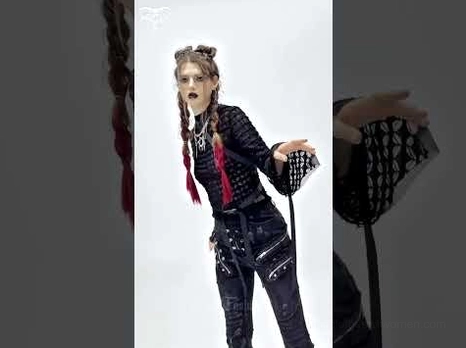 Dynamic side view of gothic punk mesh top with irregular hem and ribbon-trimmed flared sleeves on model with dark styling