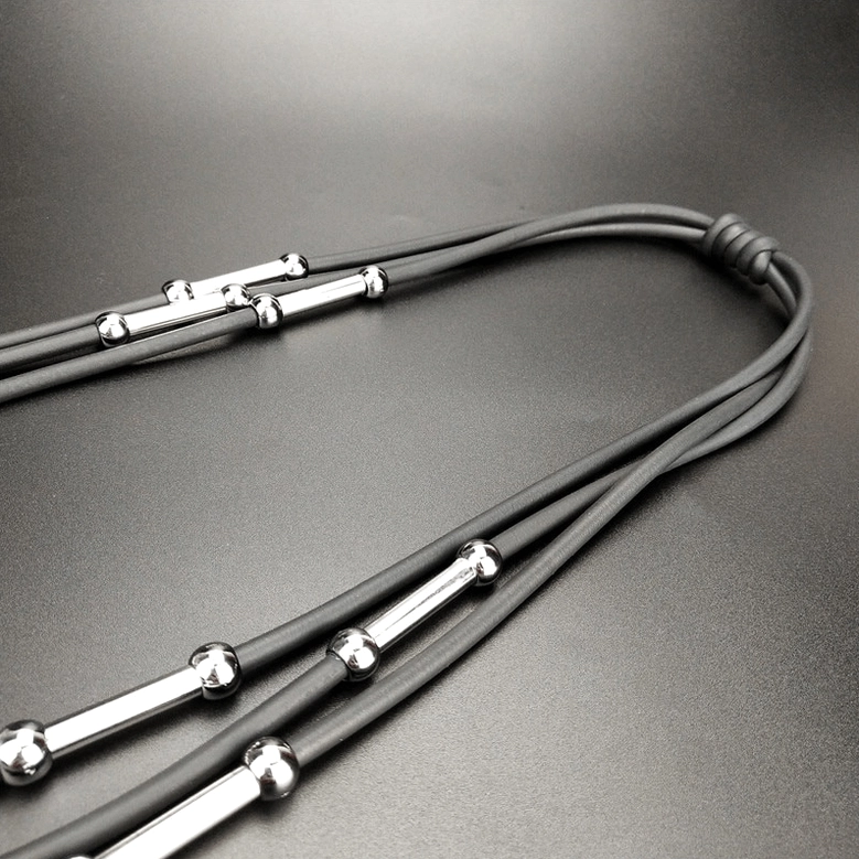 Macro close-up of gray rubber cord with silver rod and bead decorations on gothic necklace