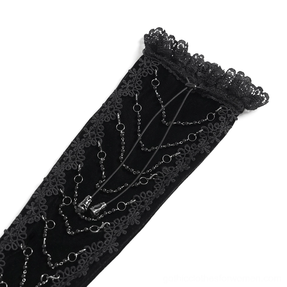 Flat lay close-up macro of black gothic opera glove back showing intricate metal chain patterns, lace trim border, and velvet texture