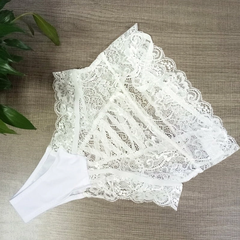White high-waisted gothic lace panties with floral scalloped edges, flat lay overhead view on wood surface