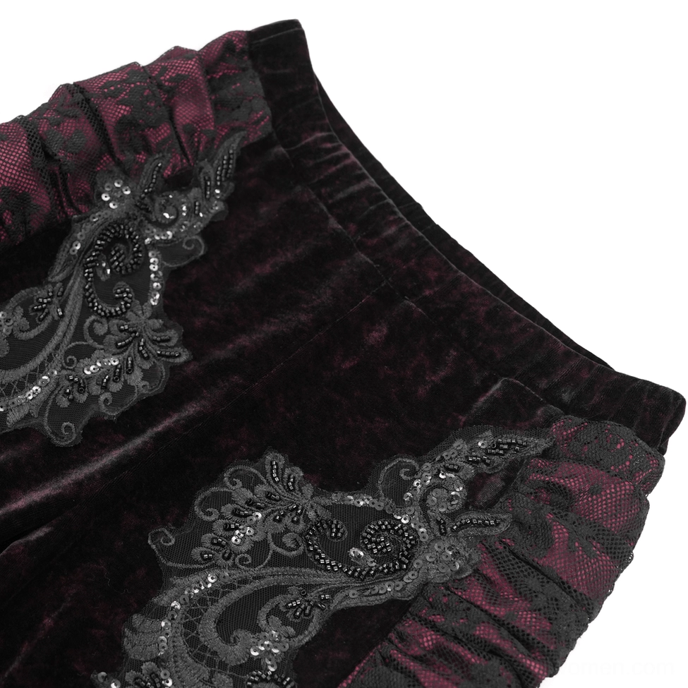 Close-up detail of beaded lace appliqué on black velvet gothic flare pants showing embroidered embellishments and ruched waist