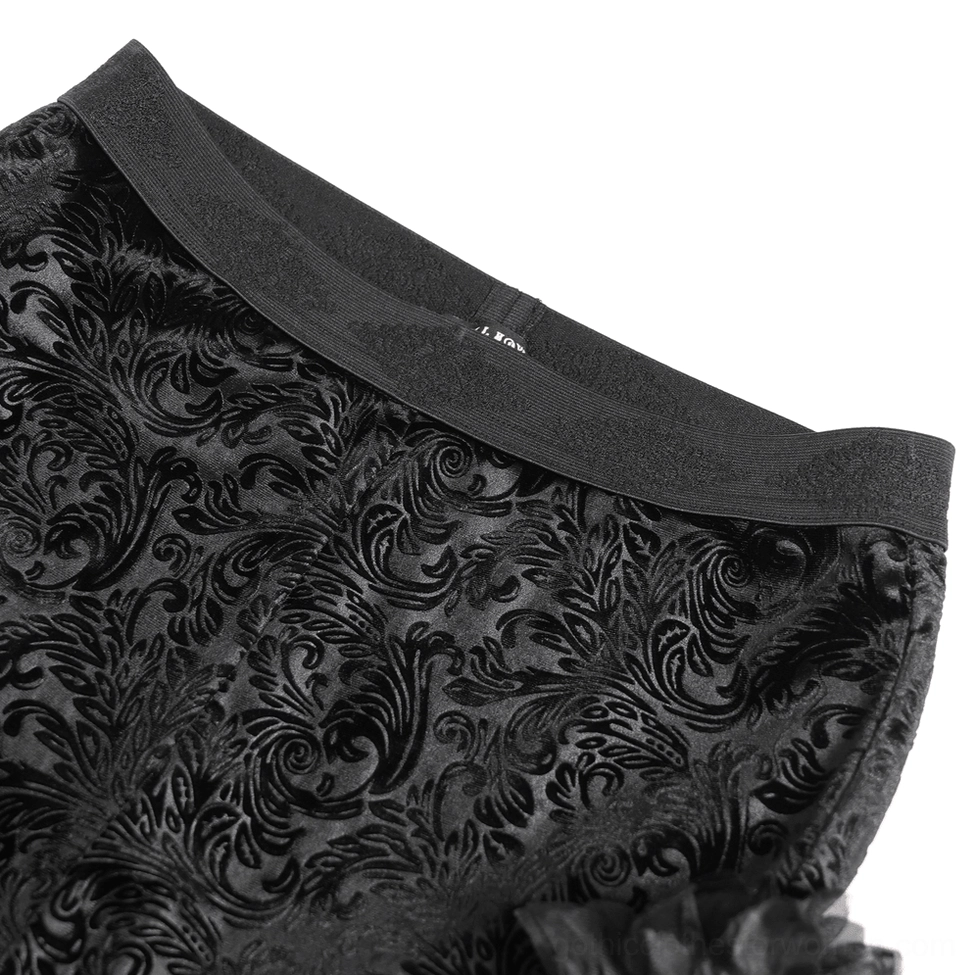 Close-up detail of black floral jacquard velvet fabric and wide elastic waistband of gothic pants
