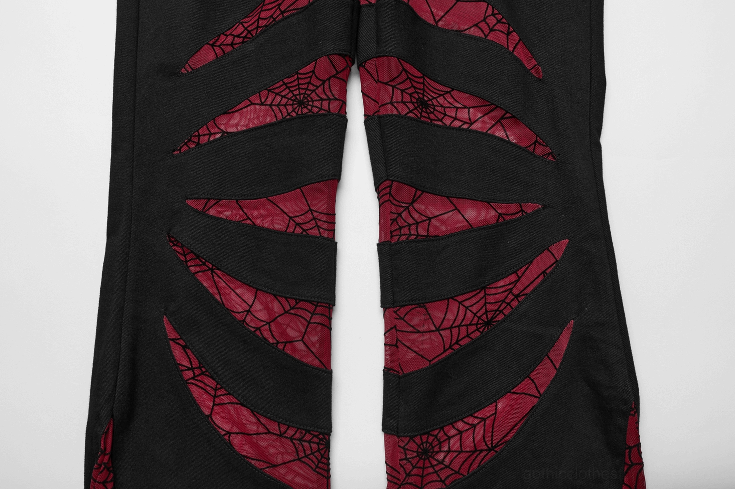 Close up stitching detail red spiderweb mesh striping on black gothic pants fabric