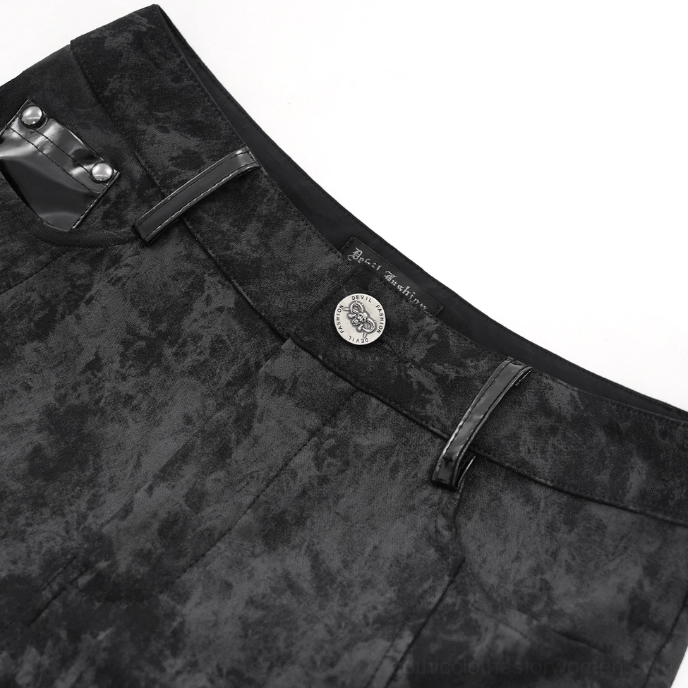 Close-up detail of gothic pants waist showing branded metal button and marbled black fabric texture