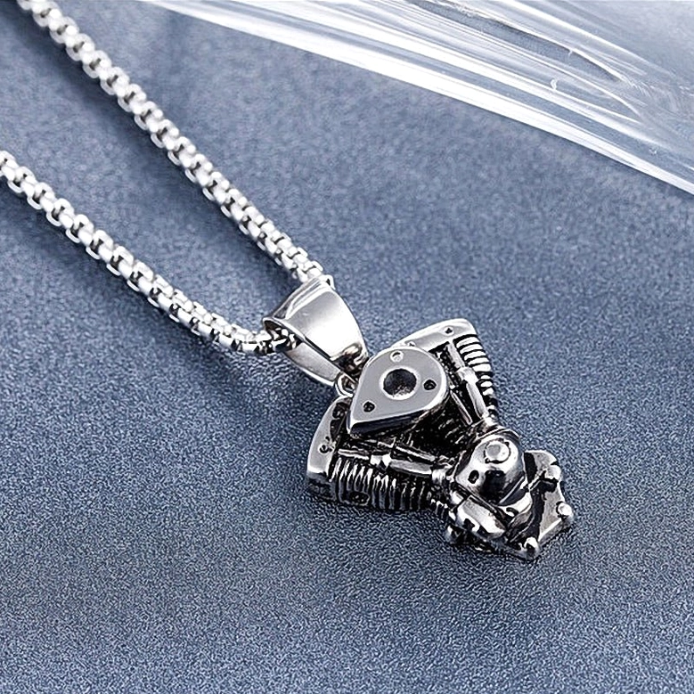 Low-angle oblique view of gothic motorcycle engine pendant displaying top and side mechanical features with antique silver patina