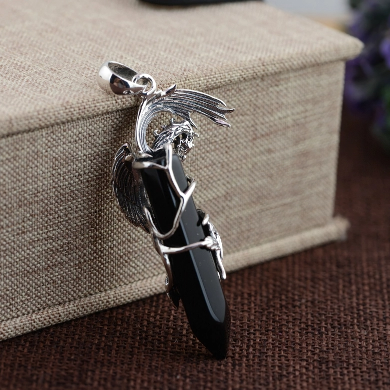 Black obsidian phoenix pendant displayed with linen packaging on natural woven mat styling shot