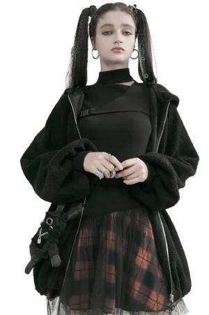 Front full-body view of black and orange plaid gothic mesh mini skirt styled with black turtleneck and fuzzy cardigan on fashion model with twin braids