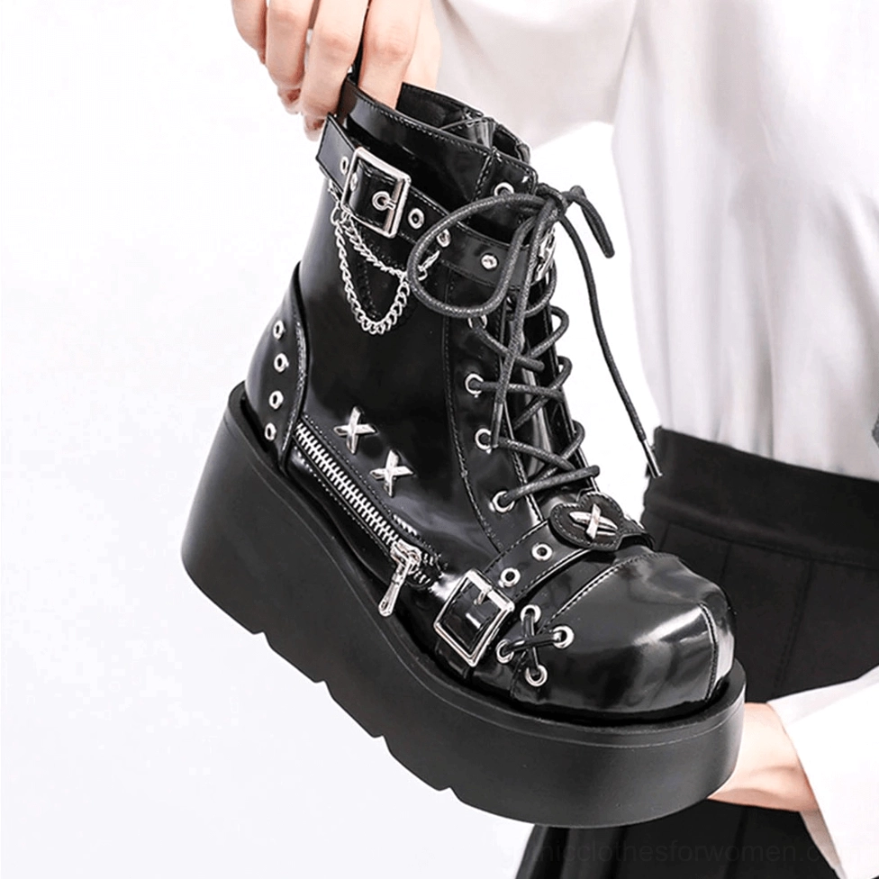 Single black gothic platform boot close-up showing chain, buckle and lace-up details held in hand