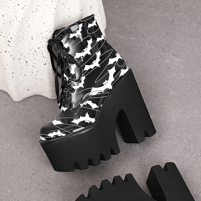Single black gothic platform boot with bat print patent leather, low angled side view on grey studio floor displaying chunky platform heel and decorative sole sample