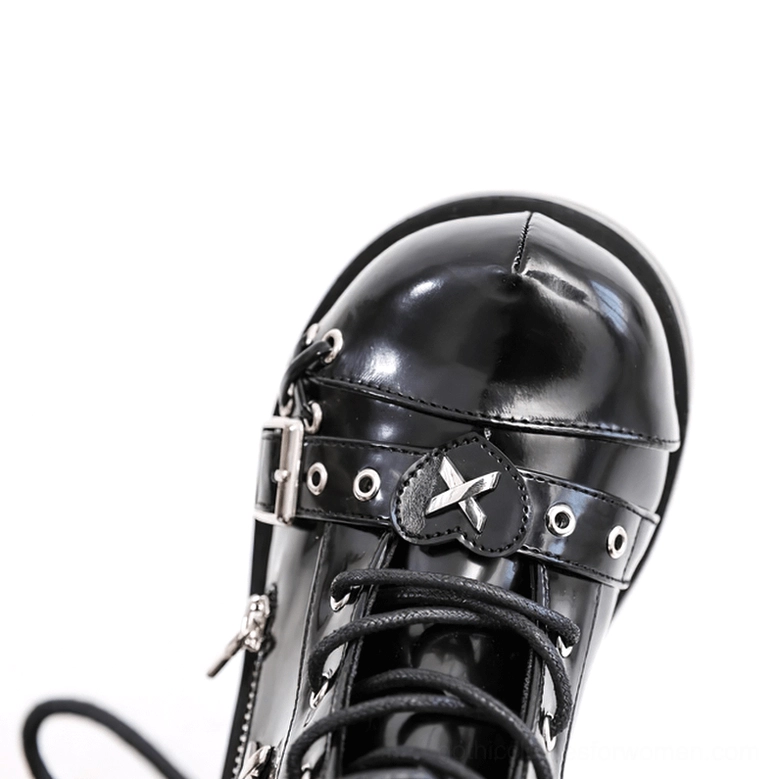Close-up of black platform boot toe area showing shiny patent leather surface with metal buckle and cross rivet decorations