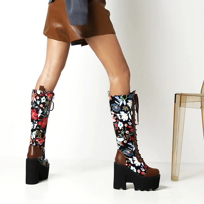 Rear angle of model in brown-accented gothic floral platform boots with lace-up closure and chunky platform sole