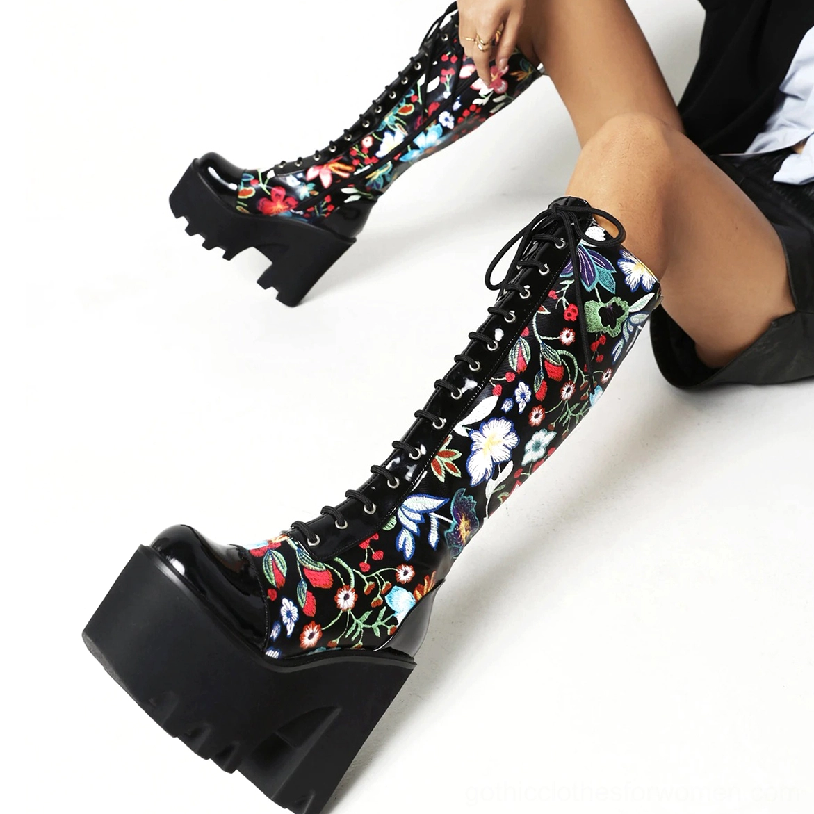 Low front angle of gothic floral platform boots showcasing patent leather toe cap and lace-up ties with chunky block heel