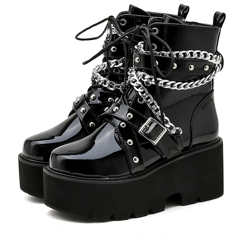 Black gothic platform combat boots with silver chain and rivet details, front view showcasing patent leather finish and square heel