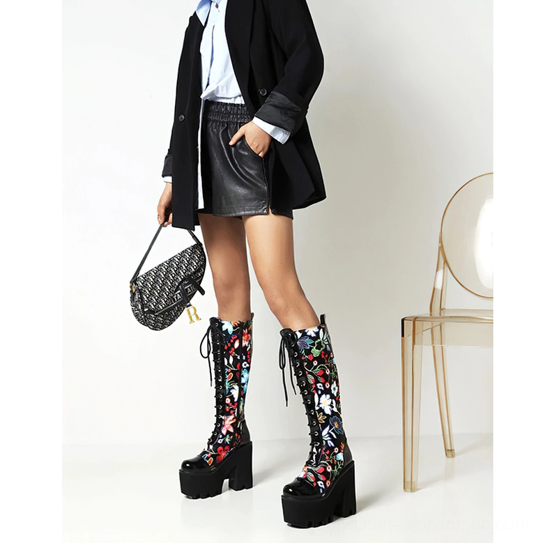 Model styled in blazer and leather skirt wearing gothic floral platform knee-high boots with matching botanical print