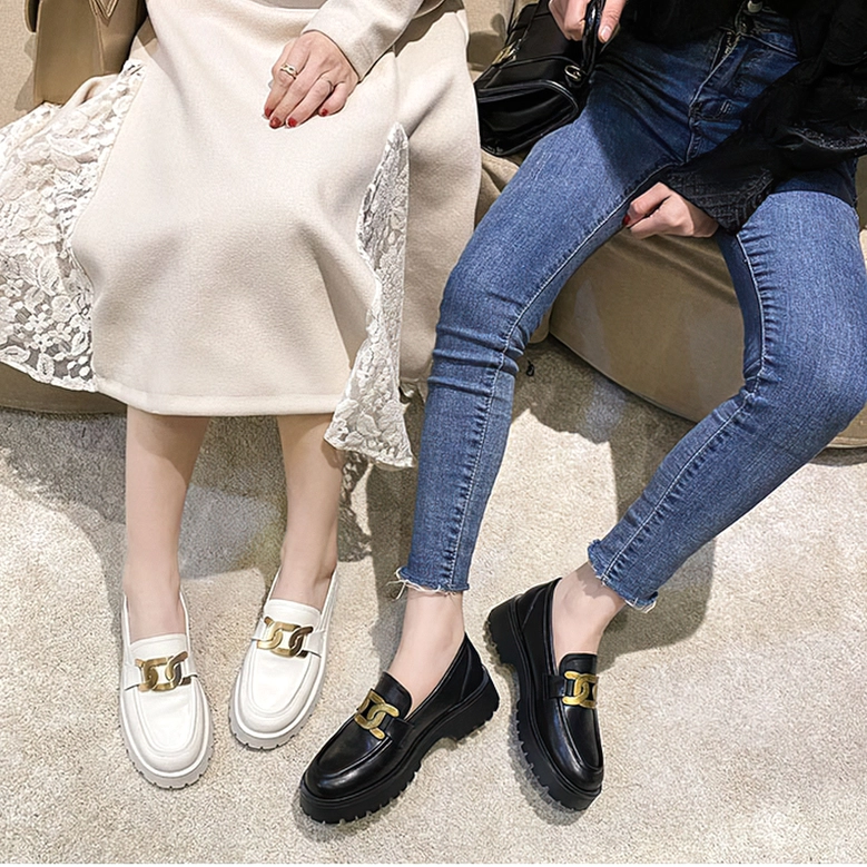 Two female models wearing gothic platform loafers in different colors on lower leg display, seated on sofa in casual indoor setting, demonstrating style versatility and comfortable wear