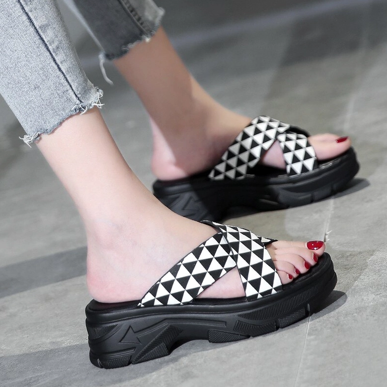 Alternative style platform sandals with bold geometric crisscross straps, featuring chunky platform sole and striking visual design