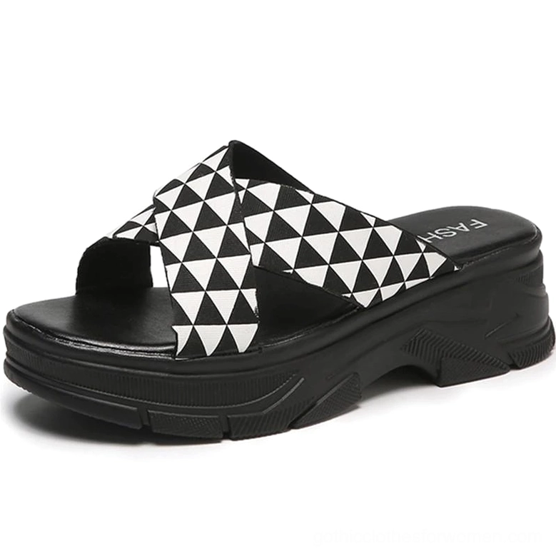 Black and white geometric crisscross platform slides with bold triangle print straps and thick rubber outsole, front angle view