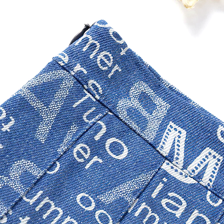 Gothic pleated denim mini skirt detailed view, all-over letter print pattern on cobalt blue fabric