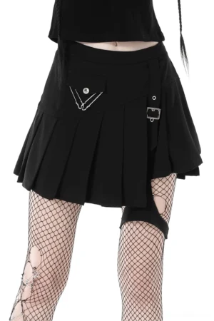 Black asymmetrical pleated punk gothic mini skirt with safety pin hardware worn by model with fishnet tights, front lower-body view