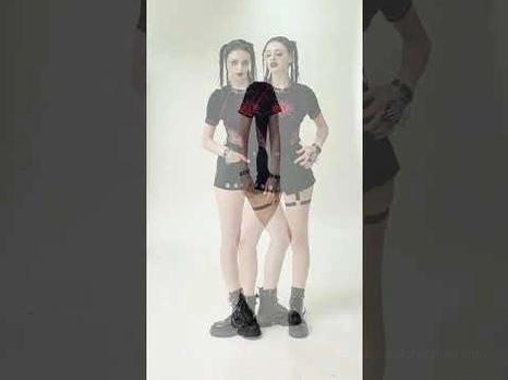 Two models wearing asymmetrical gothic pleated shorts with industrial details and O-ring straps