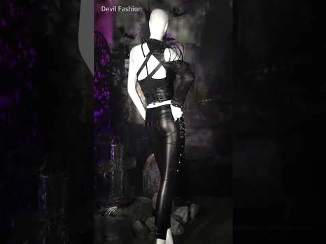 Gothic punk stage outfit featuring black lace-up cami top styled with leather pants and corset waist on fashion mannequin against dark background