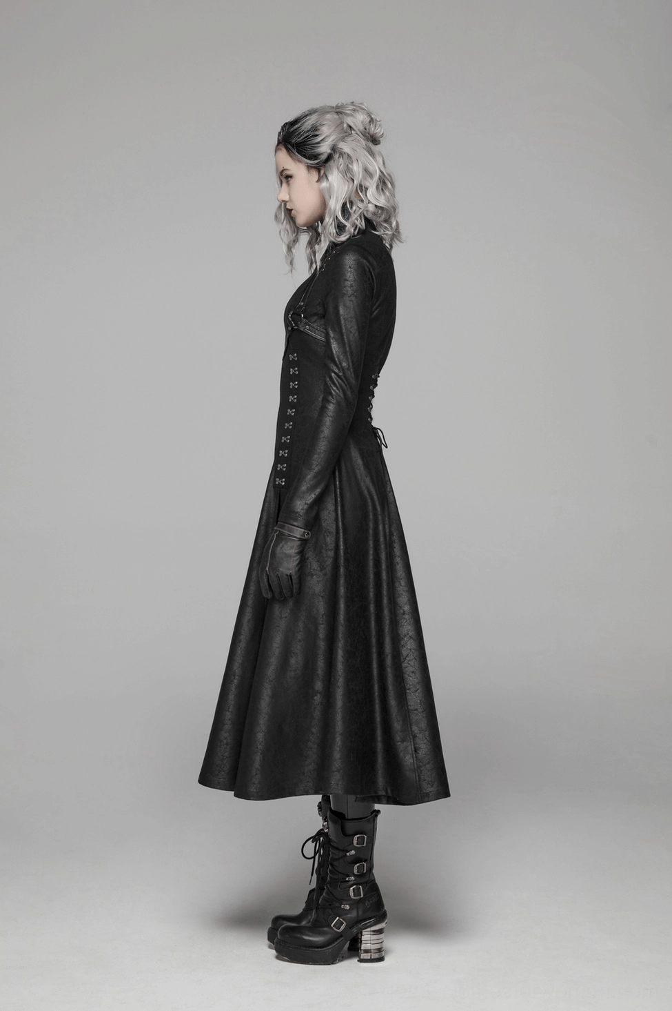 Full-length black gothic punk coat flat lay showing decorative chest straps, embossed cracking pattern, and architectural silhouette